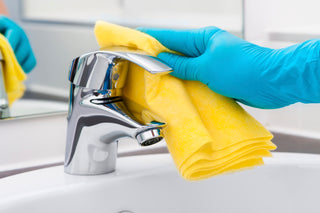 Eco-friendly cleaning sprays, brushes, and cloths on a bathroom counter